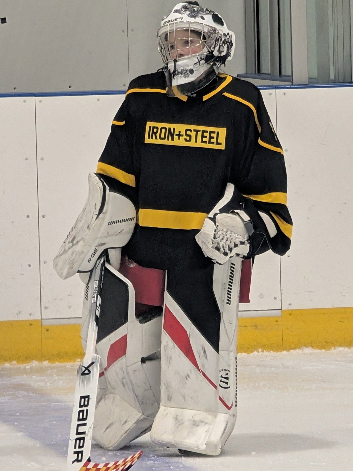 Youth goalie on the ice in a black and gold Iron+Steel jersey