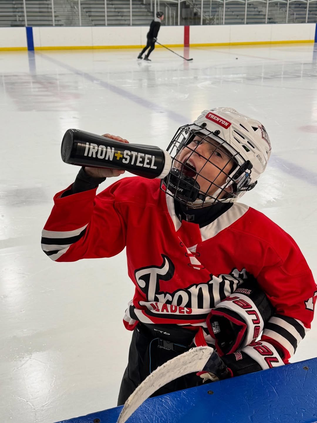 Youth player at the boards drinking from an Iron+Steel water bottle